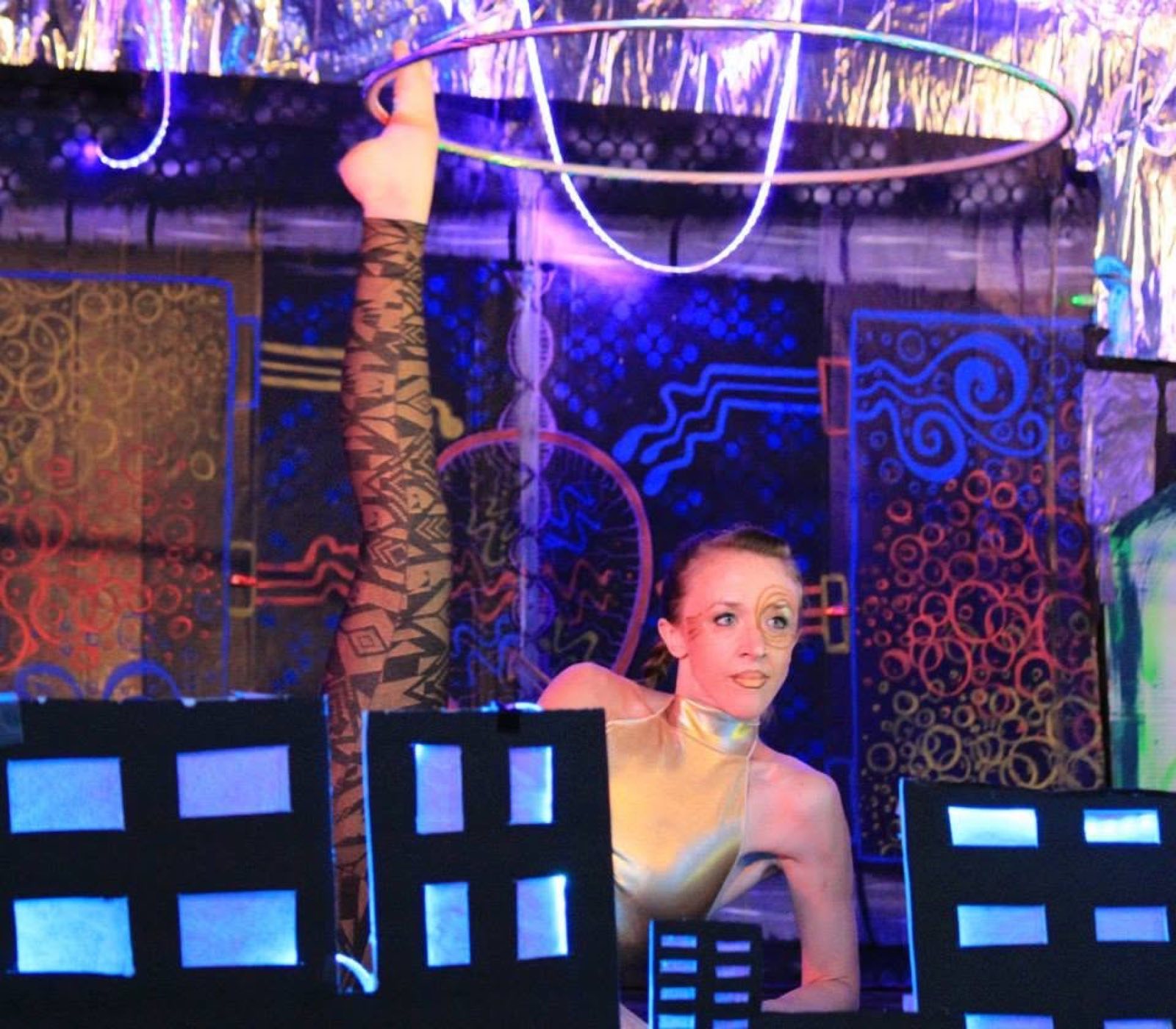Hula hoop performer framed by handmade city scenery during the 2015 Robot Apocalypse