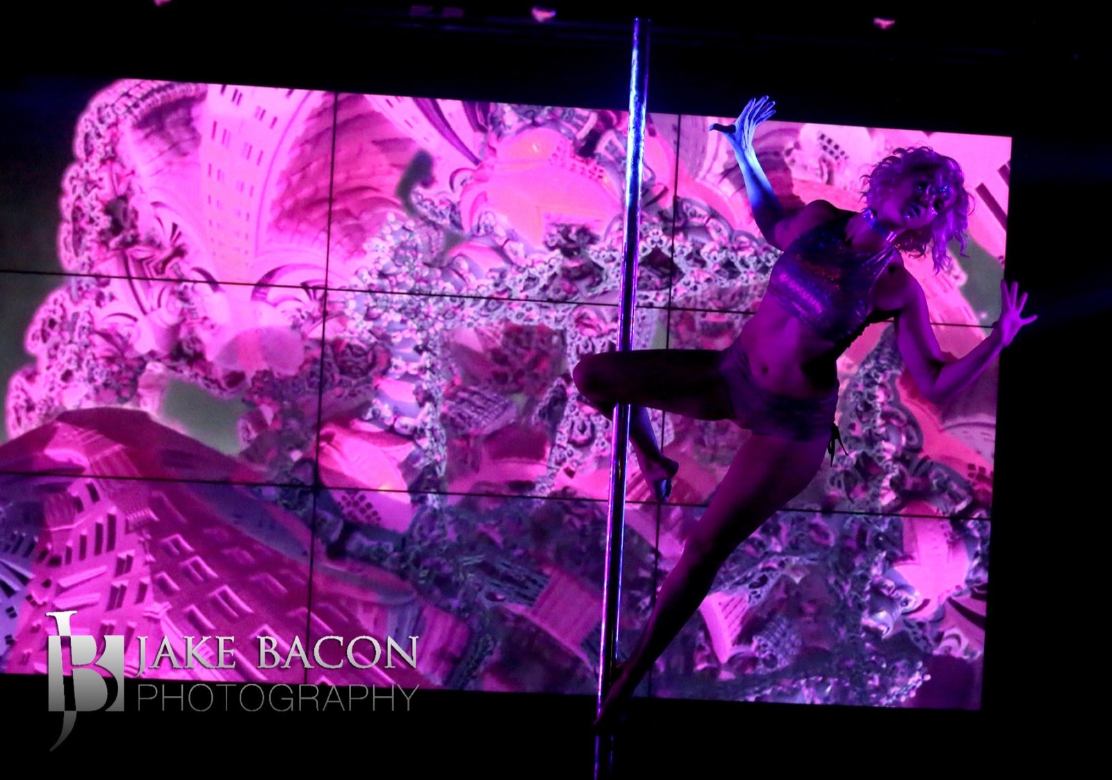 Pole performer silhouetted against vivid projected imagery during Robot Apocalypse in 2022