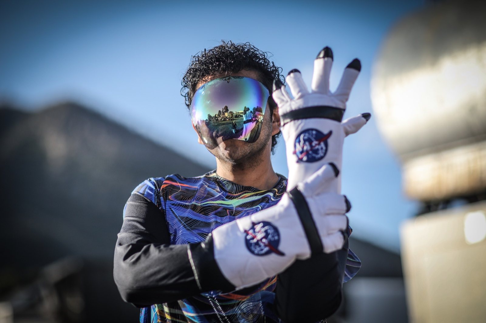 Visored performer raising a white gloved hand toward the camera
