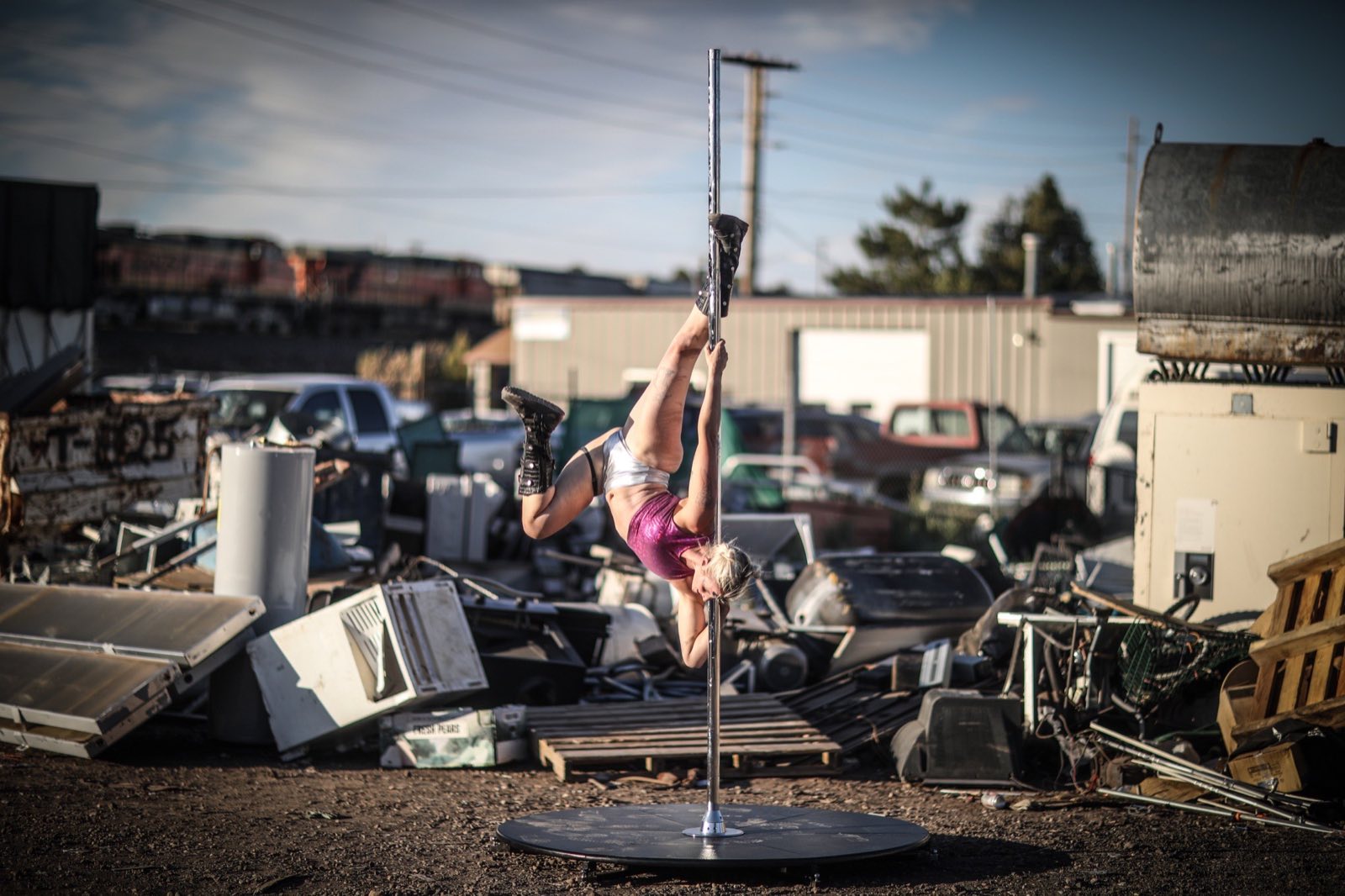 Aerial performer extending from a hoop above scattered machinery