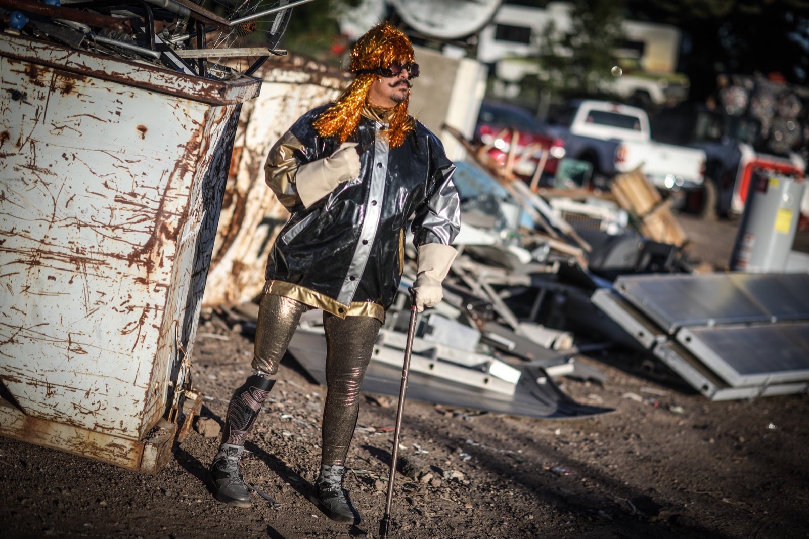 Android Dre leaning against a battered metal container in the junkyard