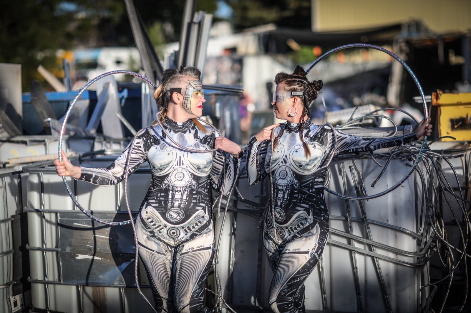 Two matching biomechanical robot characters facing each other by metal tanks