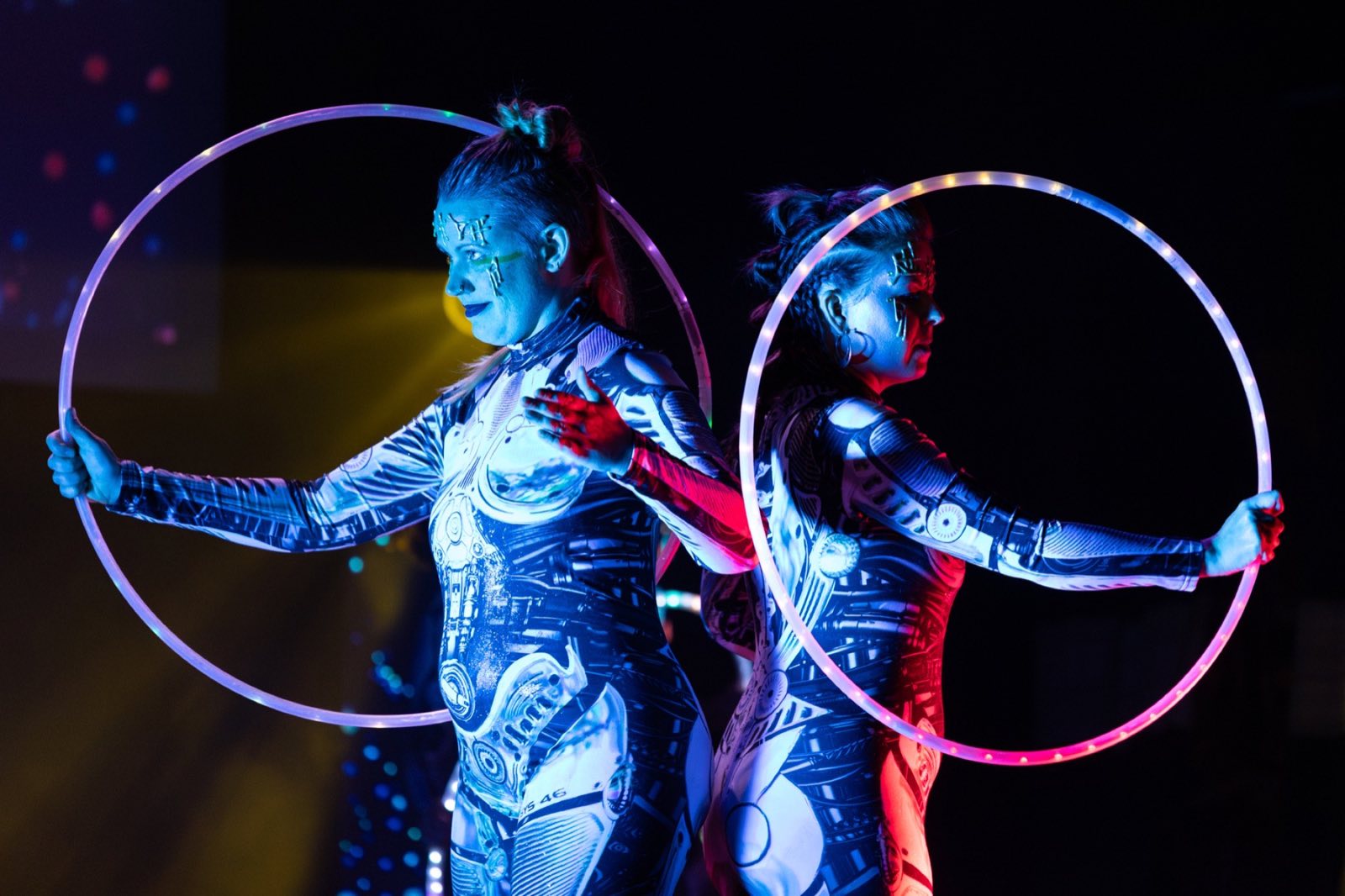 Two biomechanical robot performers holding silver hoops side by side