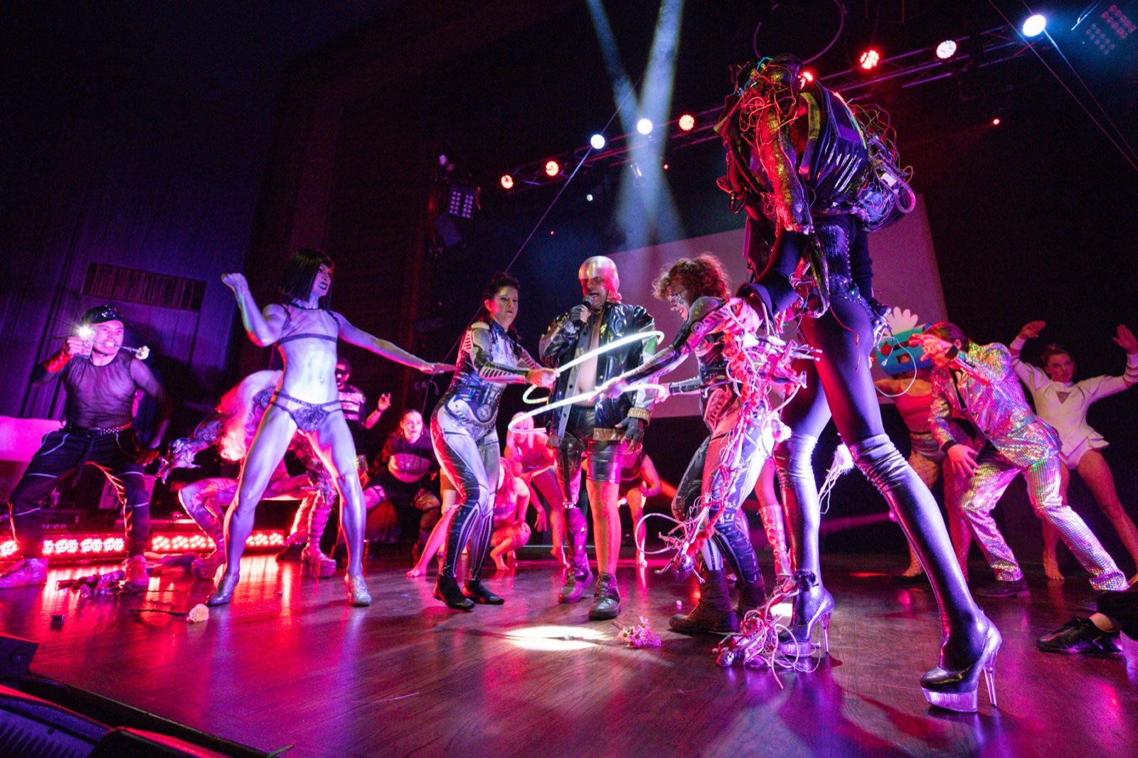Large cast moving together around a central wire-covered robot character