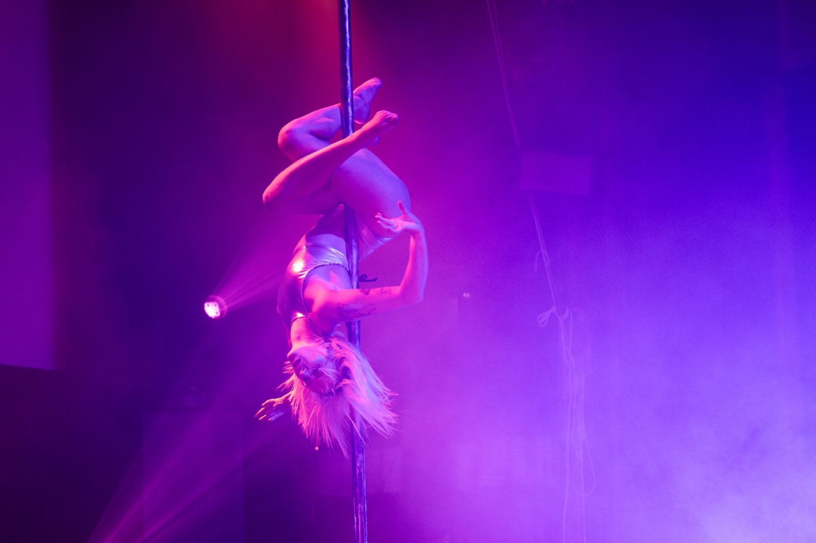 Aerialist extending from a hoop in saturated purple haze