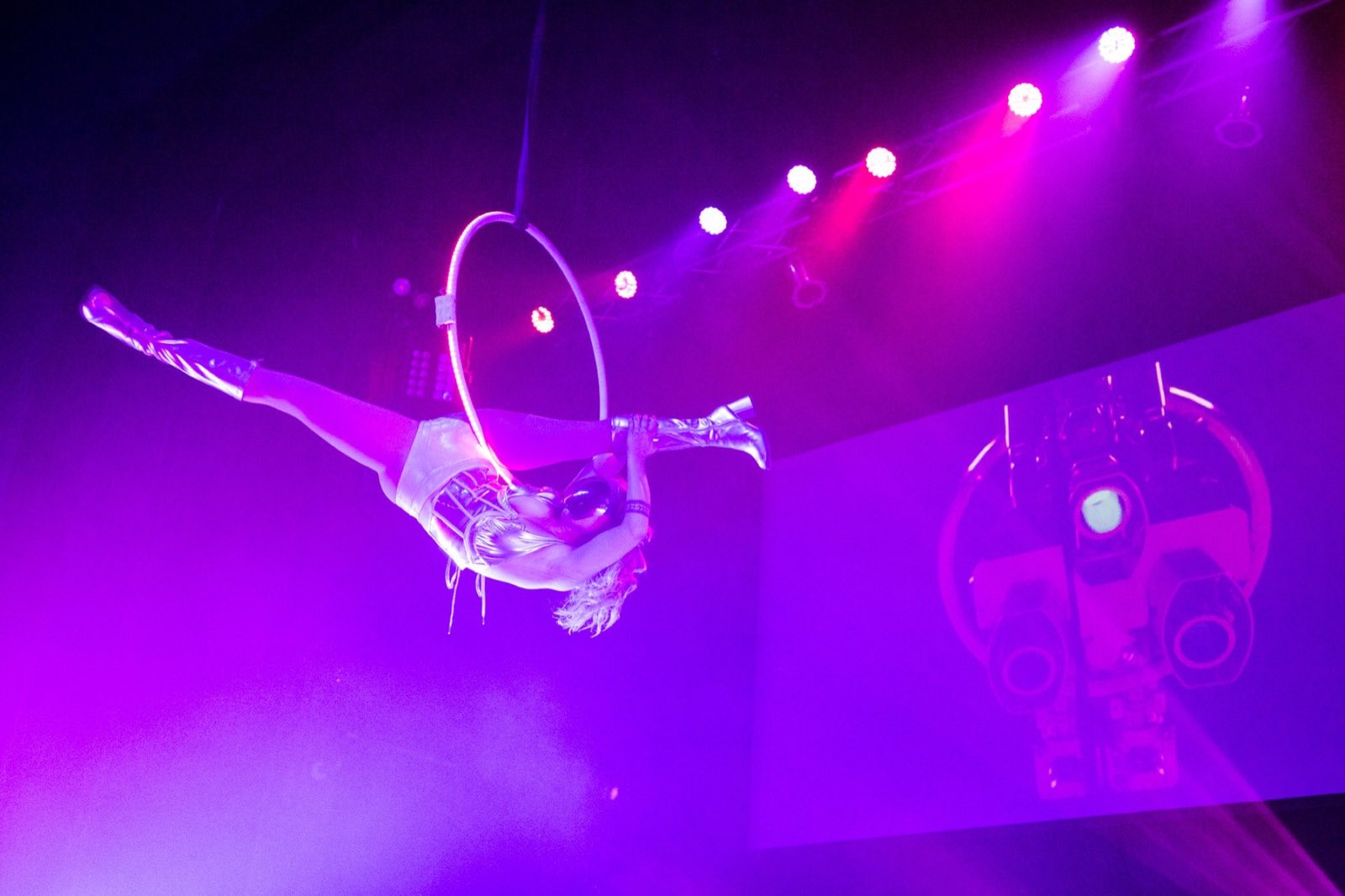 Lyra performer extending horizontally from a glowing aerial hoop