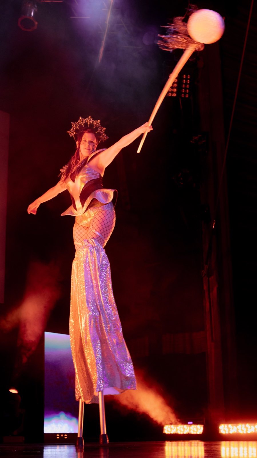 Costumed character performing in orange stage light