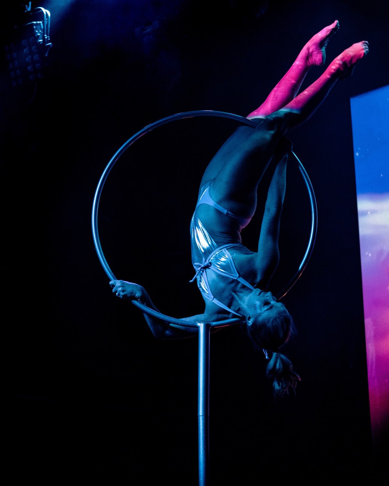 Lyra performer suspended in blue light during Worlds and Wastelands