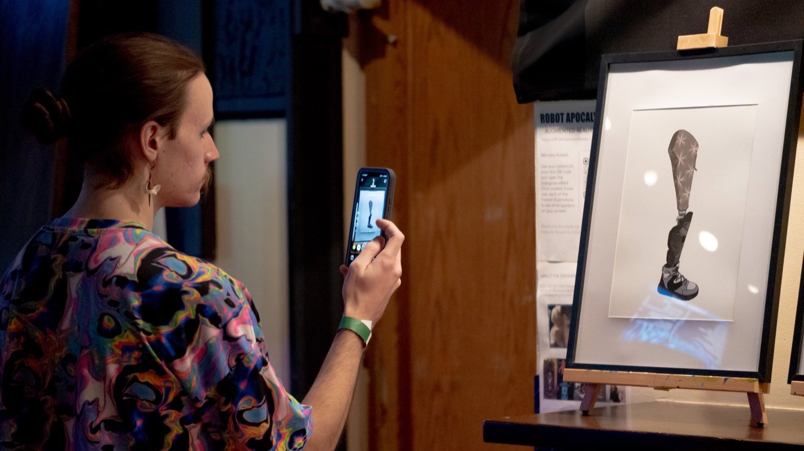 Audience member using a phone to interact with robot artwork during Worlds and Wastelands