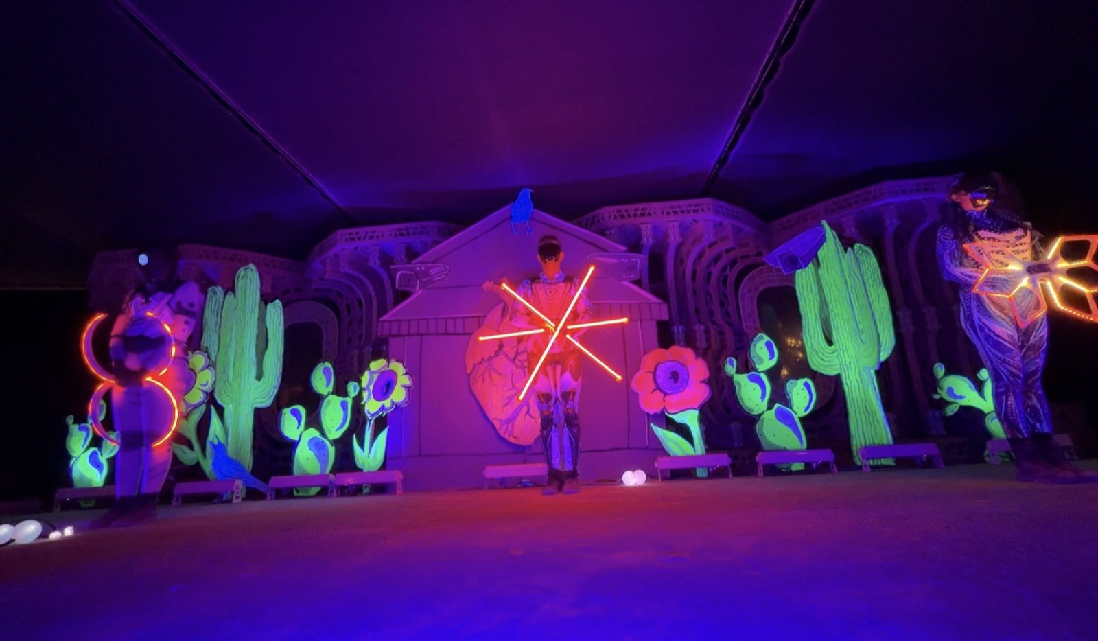 Three Hearts and Hardware performers presenting illuminated geometric props on the Center Camp stage