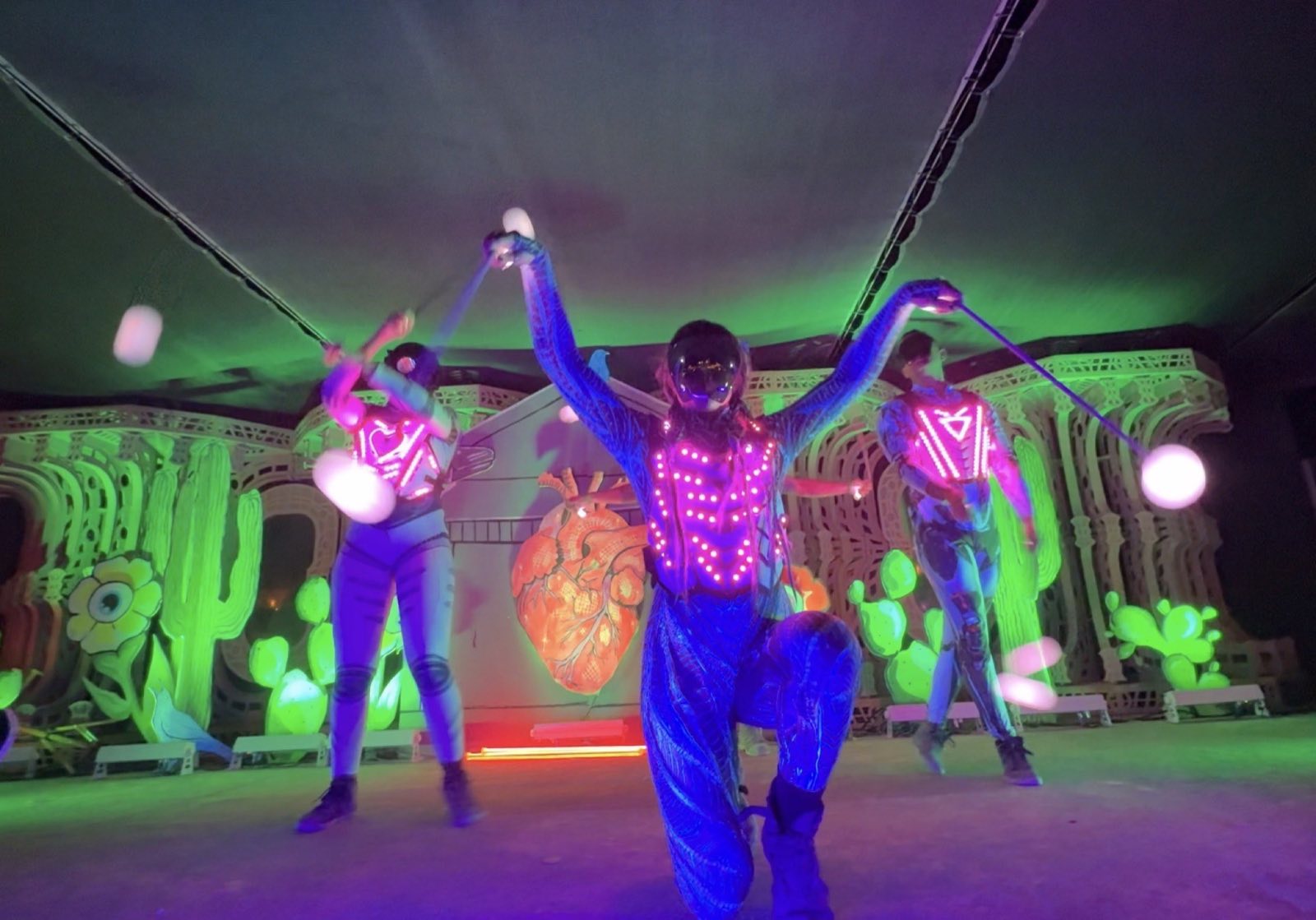 Costumed Hearts and Hardware performers moving glowing tethered props toward the audience