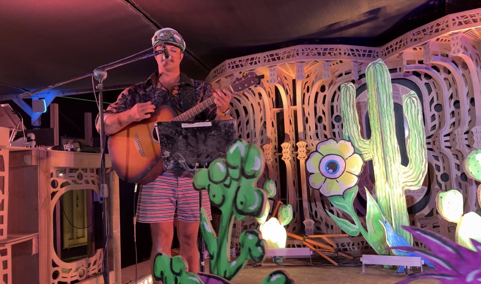A musician singing and playing guitar among the handmade desert scenery