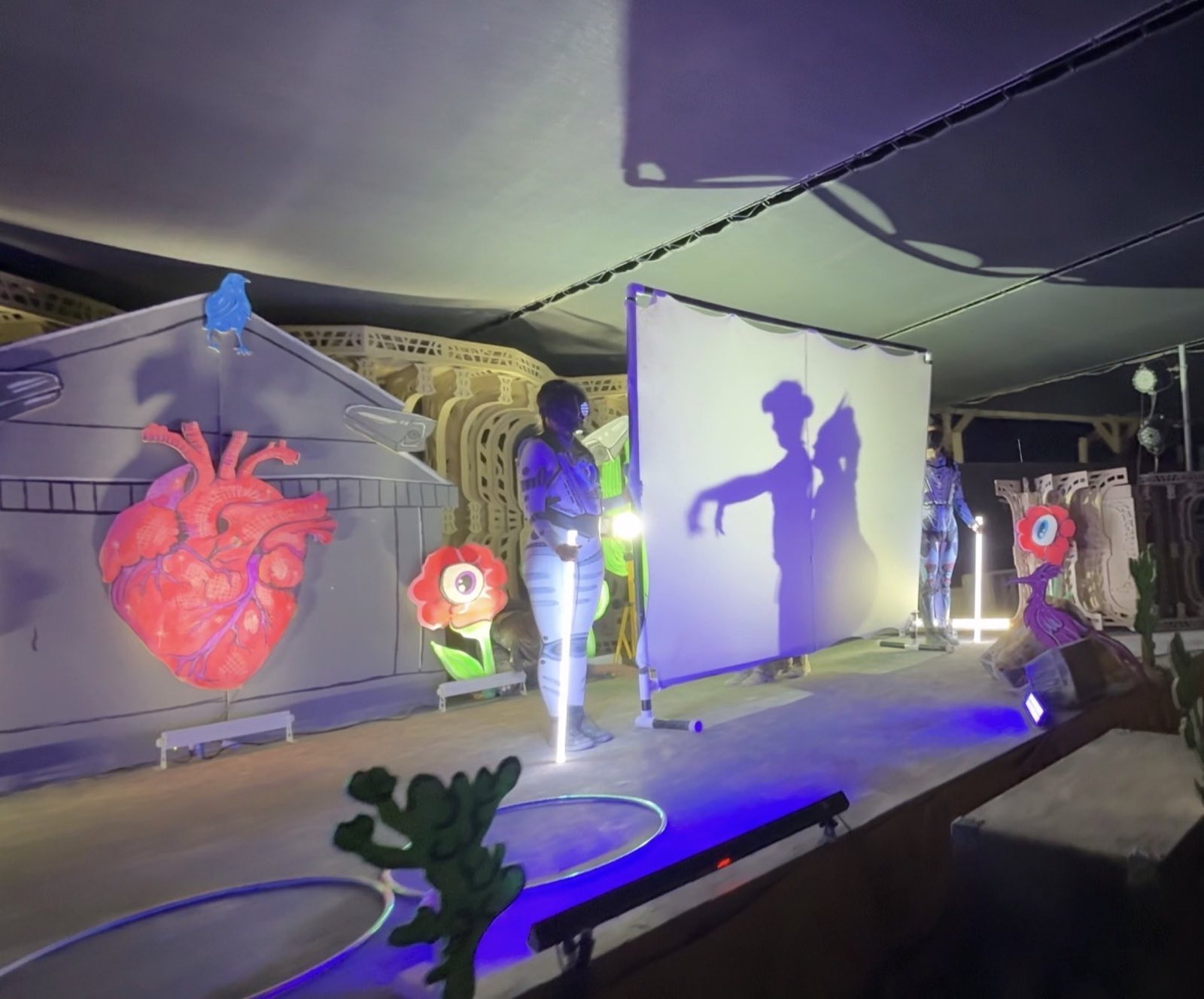 A shadow performance appearing on a translucent screen beside the illuminated stage scenery