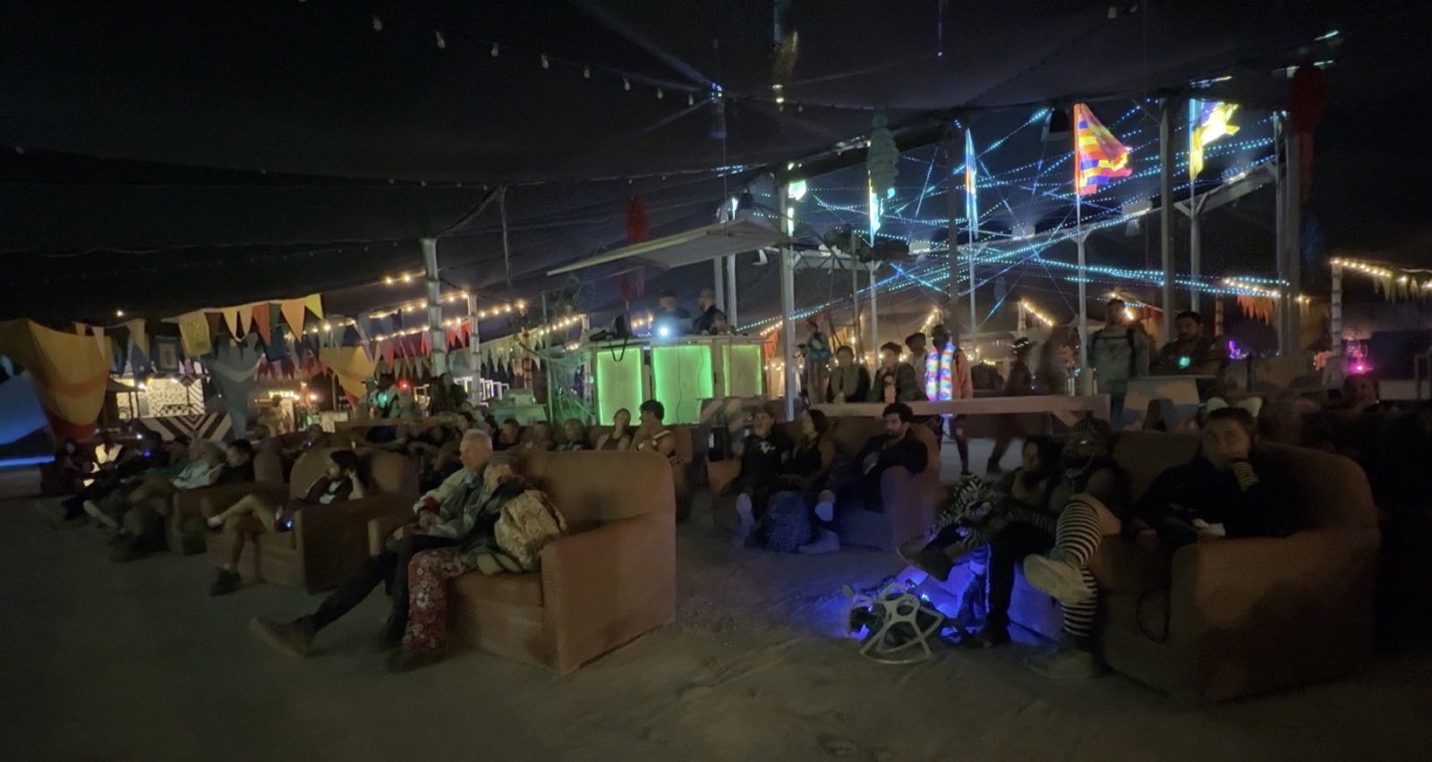 Audience members watching Hearts and Hardware from couches inside Center Camp