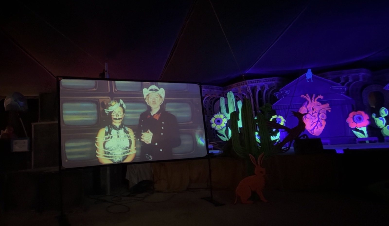 A projected narrative scene playing beside the darkened Hearts and Hardware stage