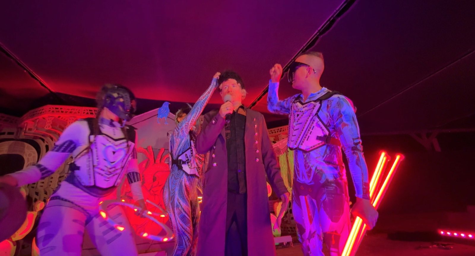 Costumed Robot Apocalypse characters perform under red and purple light at Burning Man Center Camp