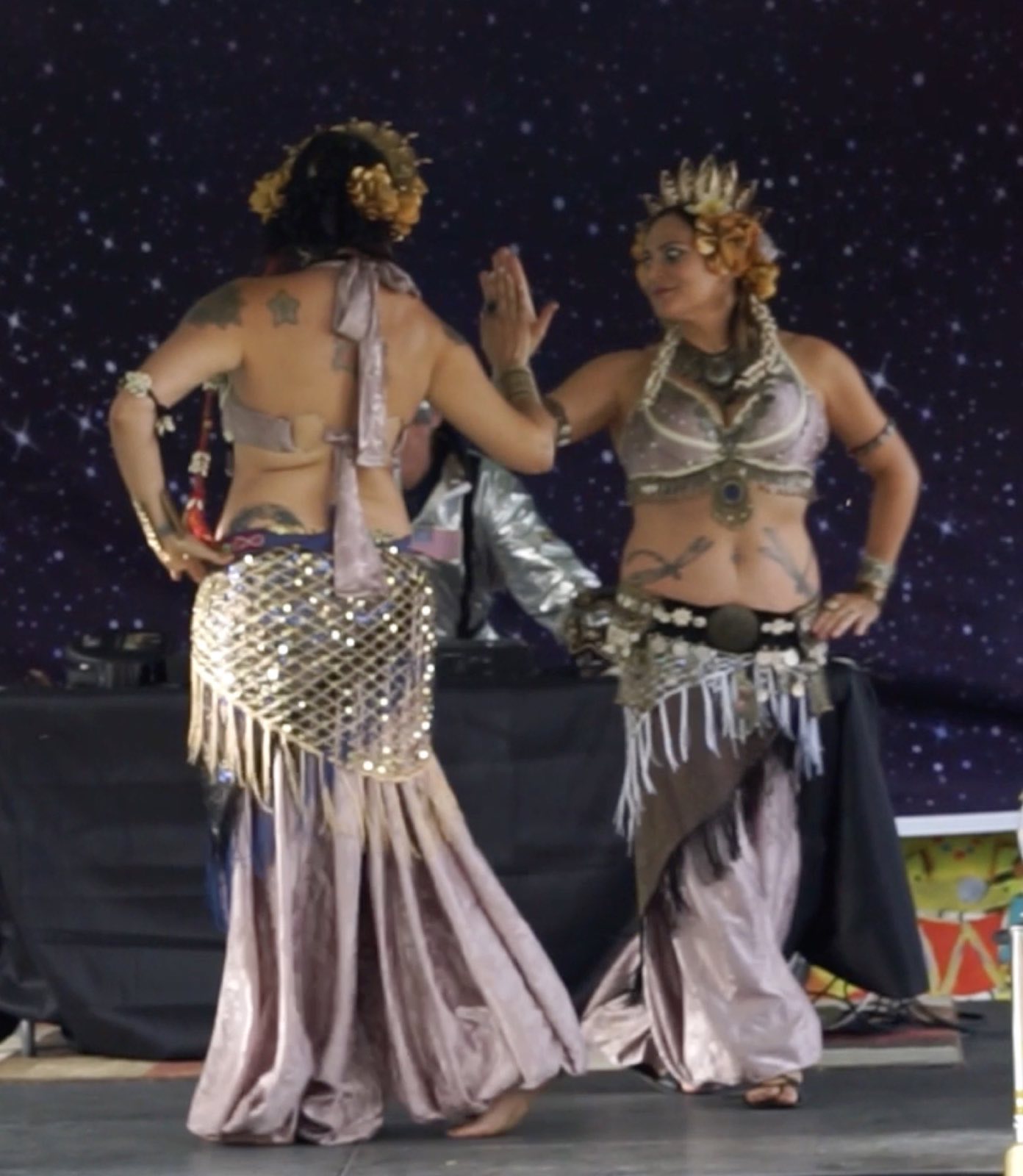 Two silver-costumed dancers facing one another onstage